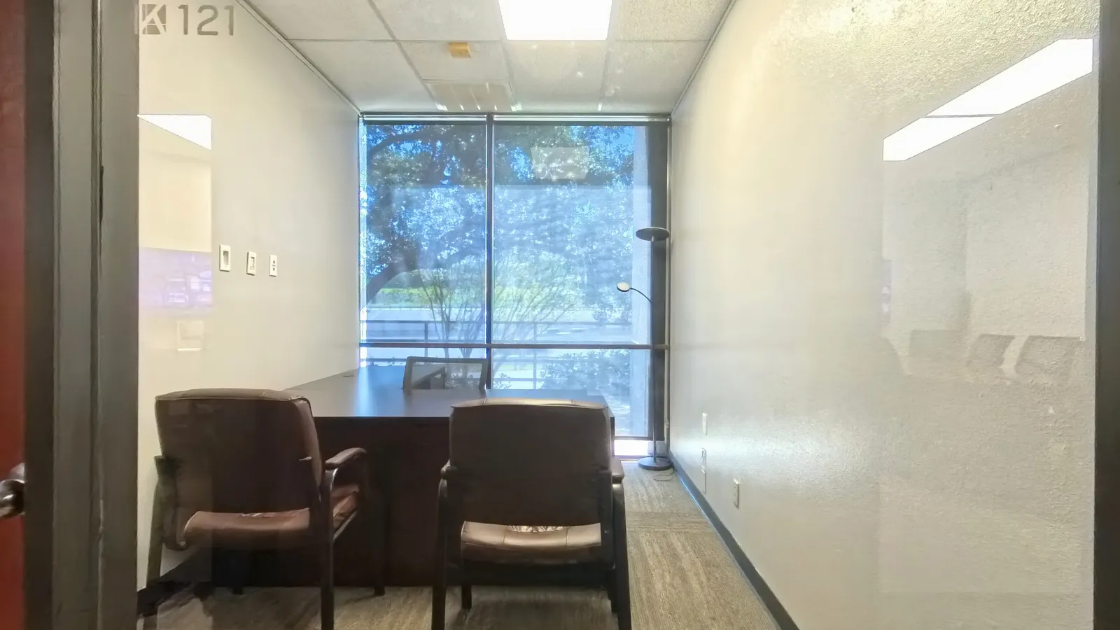 Room 121 private office with floor-to-ceiling window and tree-lined garden view