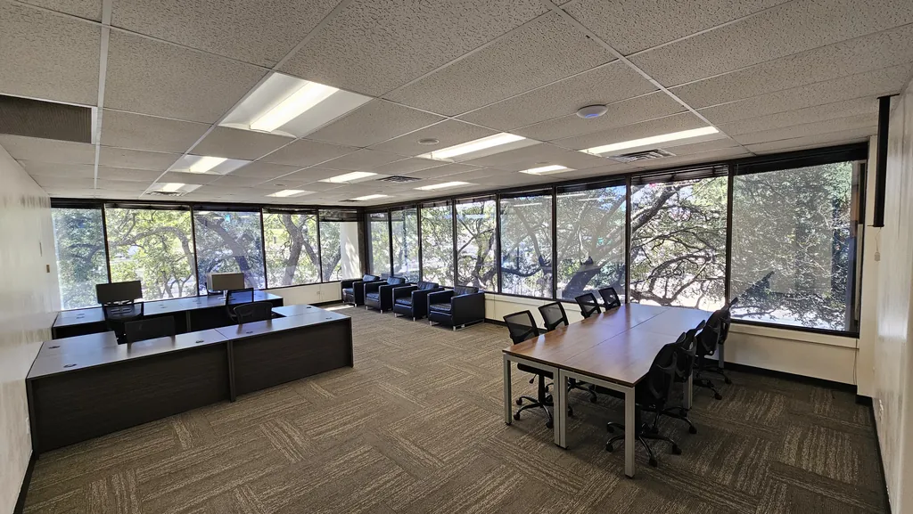 Room 221 northwest corner office with wraparound windows, desks, a conference table, and lounge seating